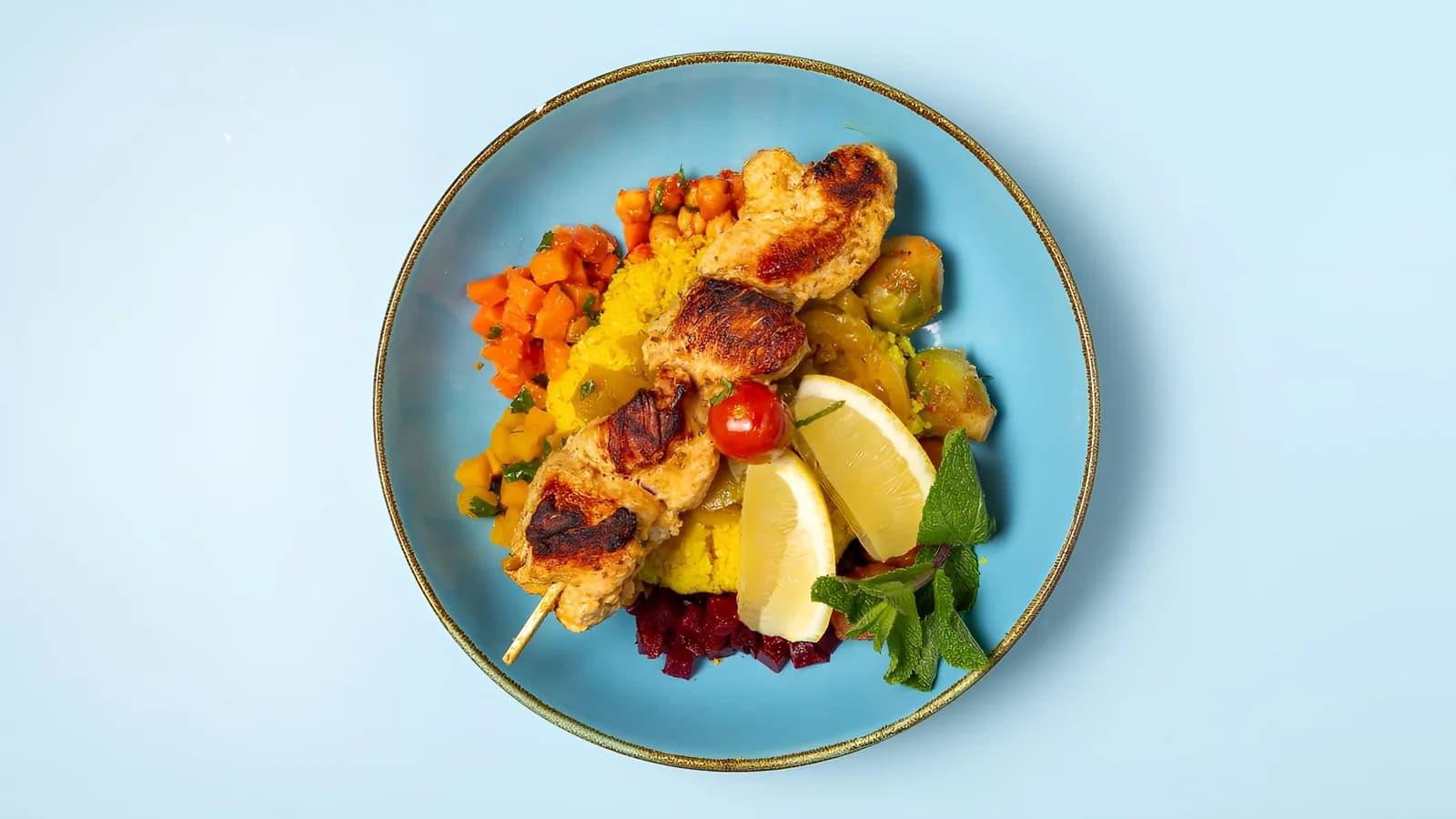 Couscous Marrakesh von oben: gegrillte Hähnchenspieße mit Zitrone auf einem blauen Teller