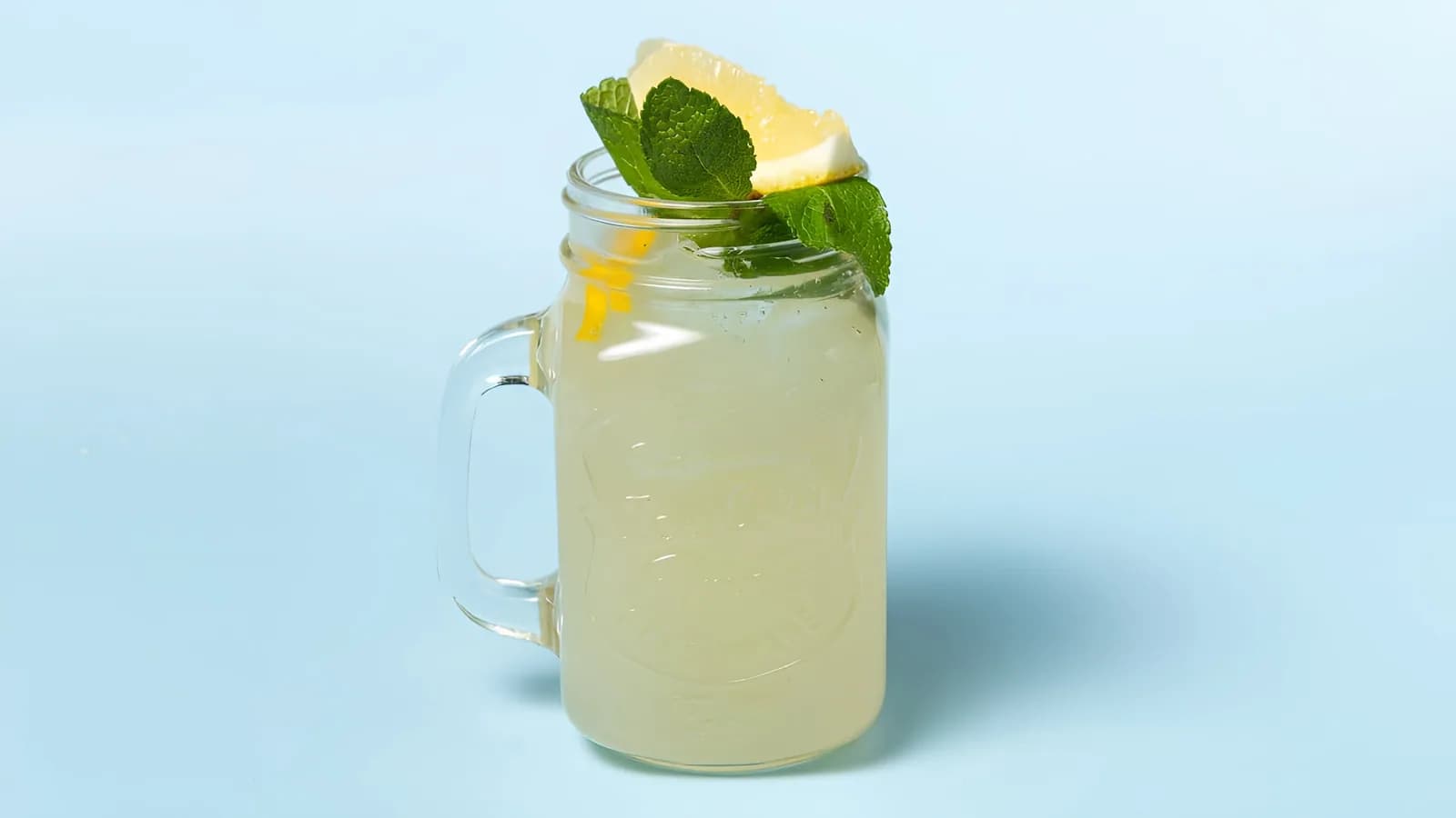 Hausgemachte Zitronenlimonade im Henkelglas mit Zitrone und Minze